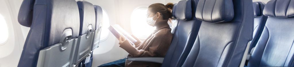 Mujer con mascarilla en el interior de un avión